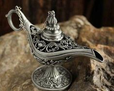 a silver teapot sitting on top of a rock