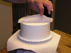 a person placing a napkin on top of a white cake