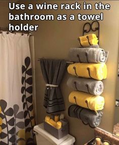 the bathroom is decorated with yellow towels and black and white shower curtain, which reads use a wine rack in the bathroom as a towel holder