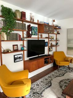 a living room filled with furniture and a flat screen tv on top of a wooden shelf