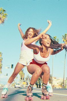 two women riding roller skates in the street with their arms around each other and smiling