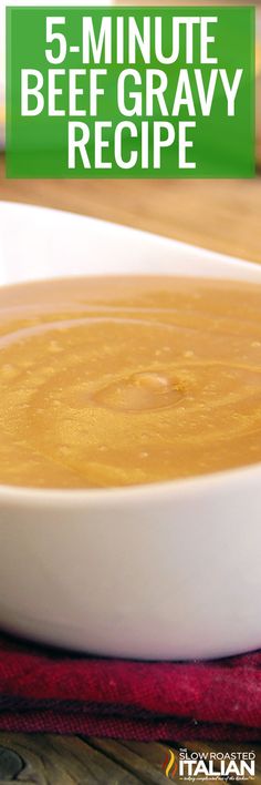 a white bowl filled with soup sitting on top of a wooden table next to a red napkin