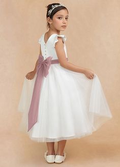 Hemi is an enchanting flower girl matte satin A-line dress that features a scoop neckline that is framed with adorable puff cap sleeves. A sash that comes to a removable bow in the back adds a charming accent. The tulle A-line silhouette allows your little one to feel delightfully free to twirl at every occasion. White Satin Princess Dress For Bridesmaid, White Satin Confirmation Dress, White Princess Style Fitted Bridesmaid Dress, White Fitted Princess Bridesmaid Dress, White Cap Sleeve Dress For Wedding, White Confirmation Dress With Satin Bow, Dusty Rose Flower Girl Dress, Satin Flower Girl Dresses, White Tulle Baptism Dress With Satin Bow