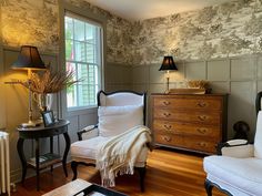 a living room with two chairs and a dresser