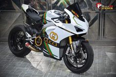 a white and green motorcycle parked in front of a glass building with the words gucci on it