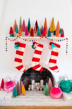 christmas stockings hanging over a fireplace with candles