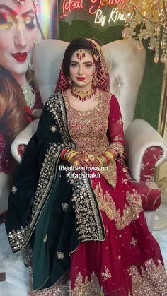 a woman sitting in a chair wearing a red and green bridal outfit with gold jewelry