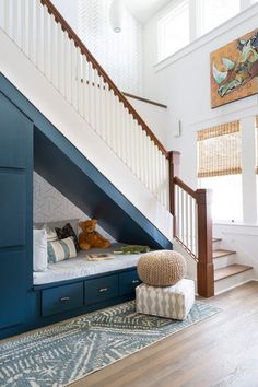 a room that has some stairs and blue cabinets in it, with a bed underneath the stairs