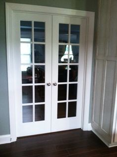 two white double doors in a room with hardwood floors