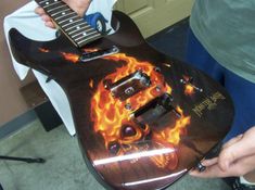 a person holding a guitar with flames on it