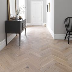 an empty room with a chair, mirror and table in the corner next to it