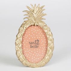 a gold pineapple frame with the words sass & belle on it