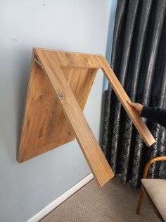 a person standing next to a chair holding a piece of wood