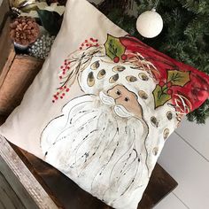 a christmas pillow sitting on top of a wooden table next to a potted plant