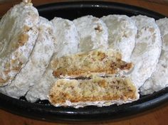 several pieces of pastries on a black plate with white powdered sugar and crumbs