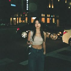 a woman is standing on the street at night with her cell phone in her hand