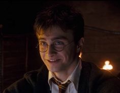 a young man wearing glasses and a tie smiling at the camera with candles in the background