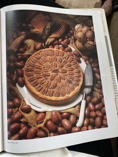 an open book with a pie on it and some nuts around the page in front of it