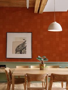 a dining room with an orange wall and wooden chairs