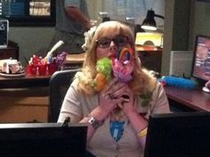 a woman sitting in front of a laptop computer holding two lollipopo rings