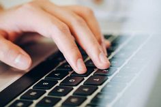 a close up of a person typing on a laptop with their hands resting on the keyboard