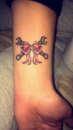 a person with a tattoo on their foot holding wrenches and a bow tie around the wrist