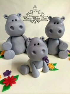 three gray hippos sitting on top of a white cake covered in frosting