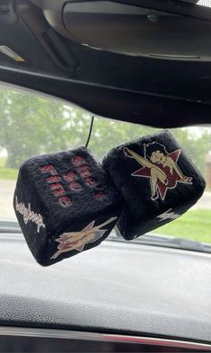 two black dices with red and white designs hanging from the side of a car