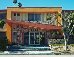 an orange building with steps leading up to it and palm trees in the front yard