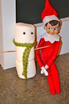 an elf is standing next to a toilet paper roll and a marshmallow on the ground