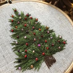 a cross - stitch christmas tree with red and green ornaments on it's branches