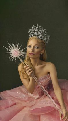 a woman in a pink dress holding a wand and wearing a tiara with stars on it