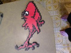 a cross - stitch image of a red and black cartoon character on a tile floor