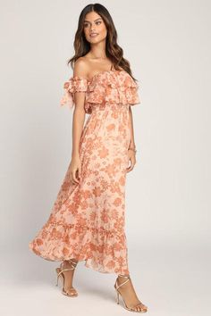 a woman wearing an off the shoulder dress with flowers and ruffles on it