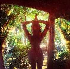 a woman is standing in the sun with her hands behind her head