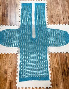 a blue knitted sweater laying on top of a wooden floor