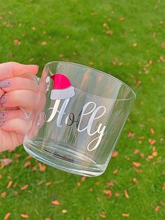 a person holding a clear cup with the word holly on it and a santa hat