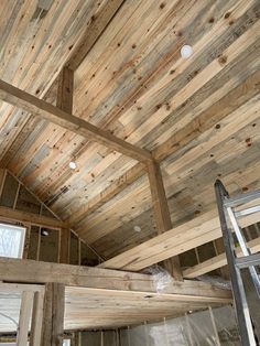 the inside of a building with wooden walls and beams on the ceiling, ladders to the roof