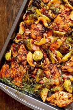 chicken and brussel sprouts in a roasting pan on a wooden table