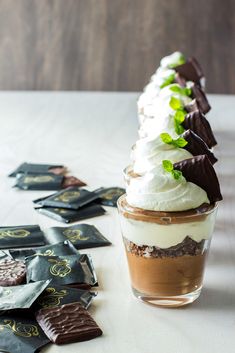 there is a dessert with chocolate and whipped cream in it on the table next to some candy