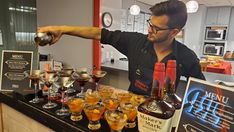 a man pouring drinks into glasses at a bar