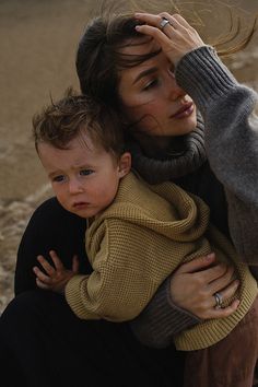 a woman holding a baby in her arms while she holds the child's head