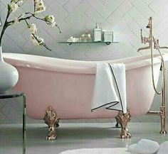 a pink bath tub sitting in a bathroom next to a vase with flowers on it