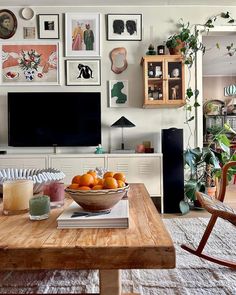 a bowl of oranges sitting on top of a wooden table in front of a tv