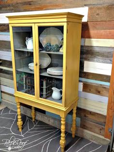 a yellow china cabinet with plates and bowls in it