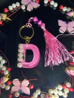 the letter d is surrounded by beads and other items such as keychains, butterflies, and pearls