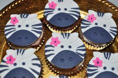 cupcakes decorated like zebras and flowers on a gold platter with foil wrappers