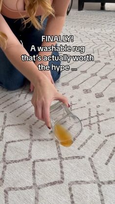 a woman sitting on the floor with an empty glass bottle in her hand and a caption that reads, finally a washable rug that's actually worth the hyp?