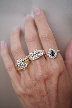 a woman's hand with three different rings on her left and the other one is wearing