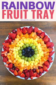 a white plate topped with fruit on top of a wooden table next to a sign that says rainbow fruit tray